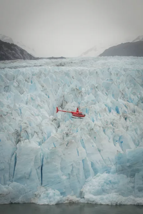 Helicopter flying close to a large glacier
