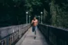 Shirtless man running across wood bridge