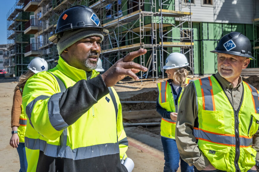 Construction worker points up at something while another looks
