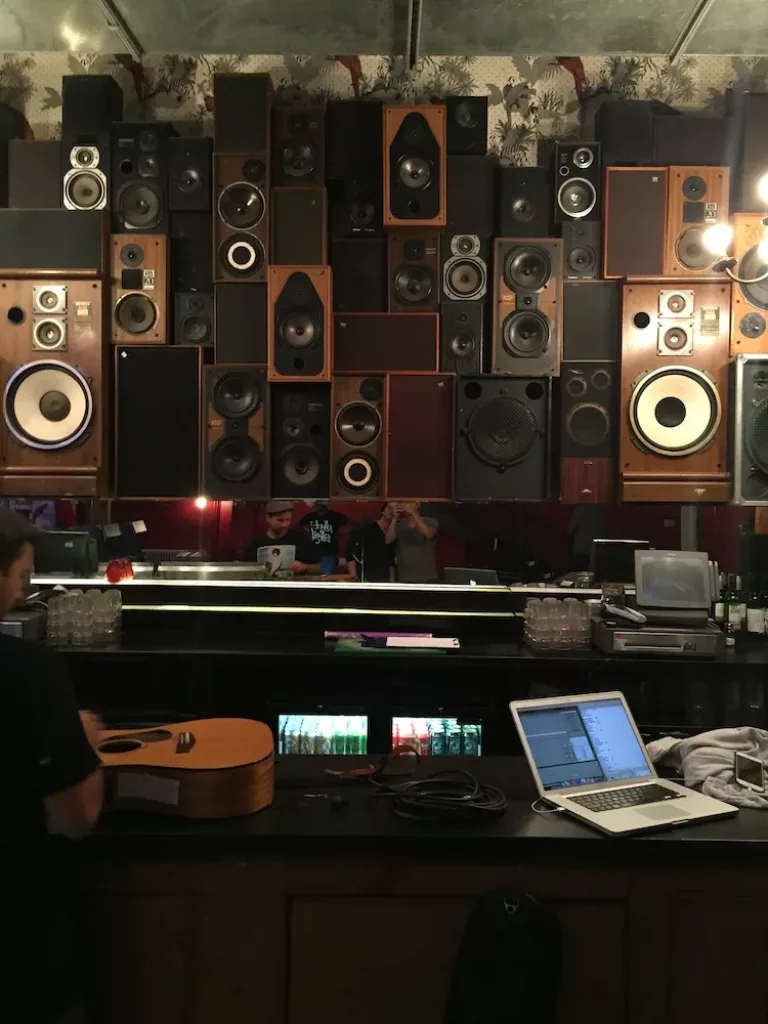 Wall of speakers, a guitar and a laptop in a music studio