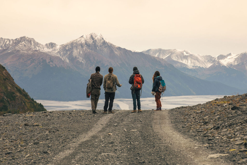 Four people on a road hiking in alaska