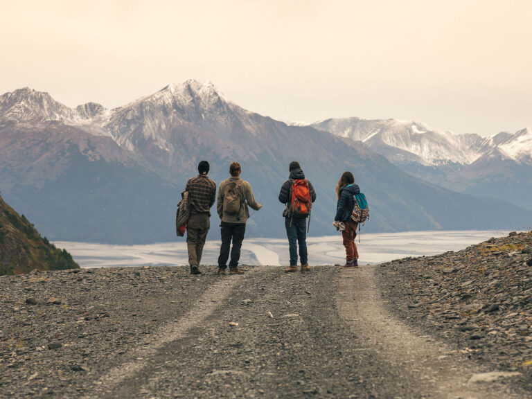 Four people on a road hiking in alaska